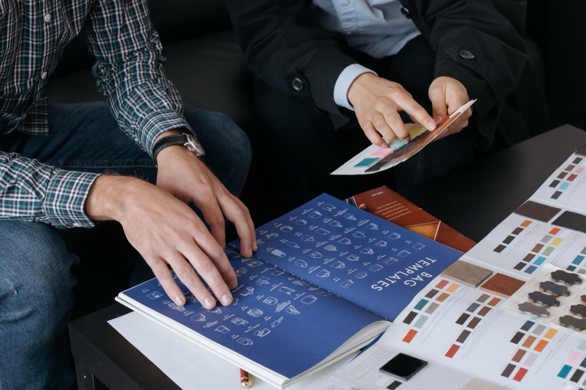 A designer's hands organizing brand identity assets and color palettes.