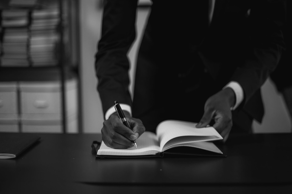 Hand die een merkstrategie opschrijft in een notitieboek met een vulpen.
