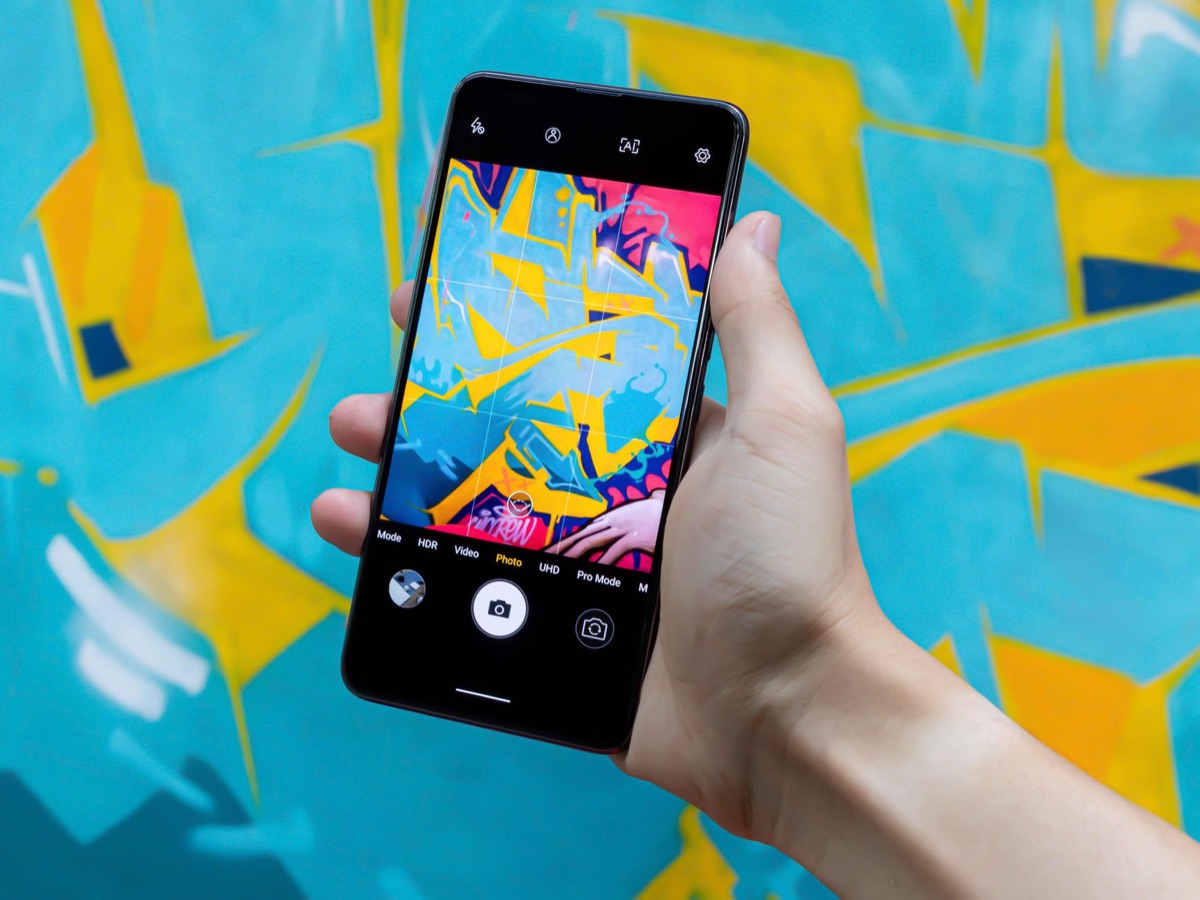Mão segurando um smartphone exibindo gráficos de identidade visual de marca.