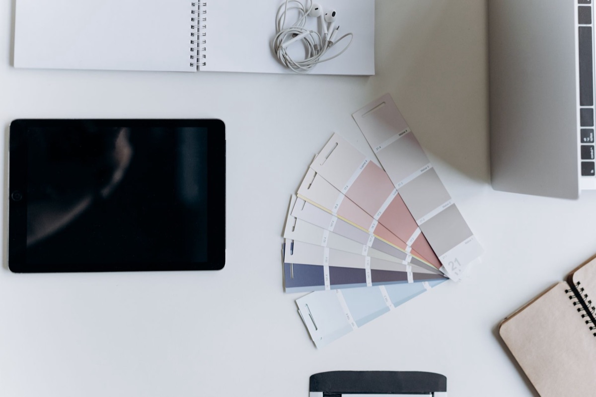 Mesa organizada com guia de estilo de marca impresso e um tablet.
