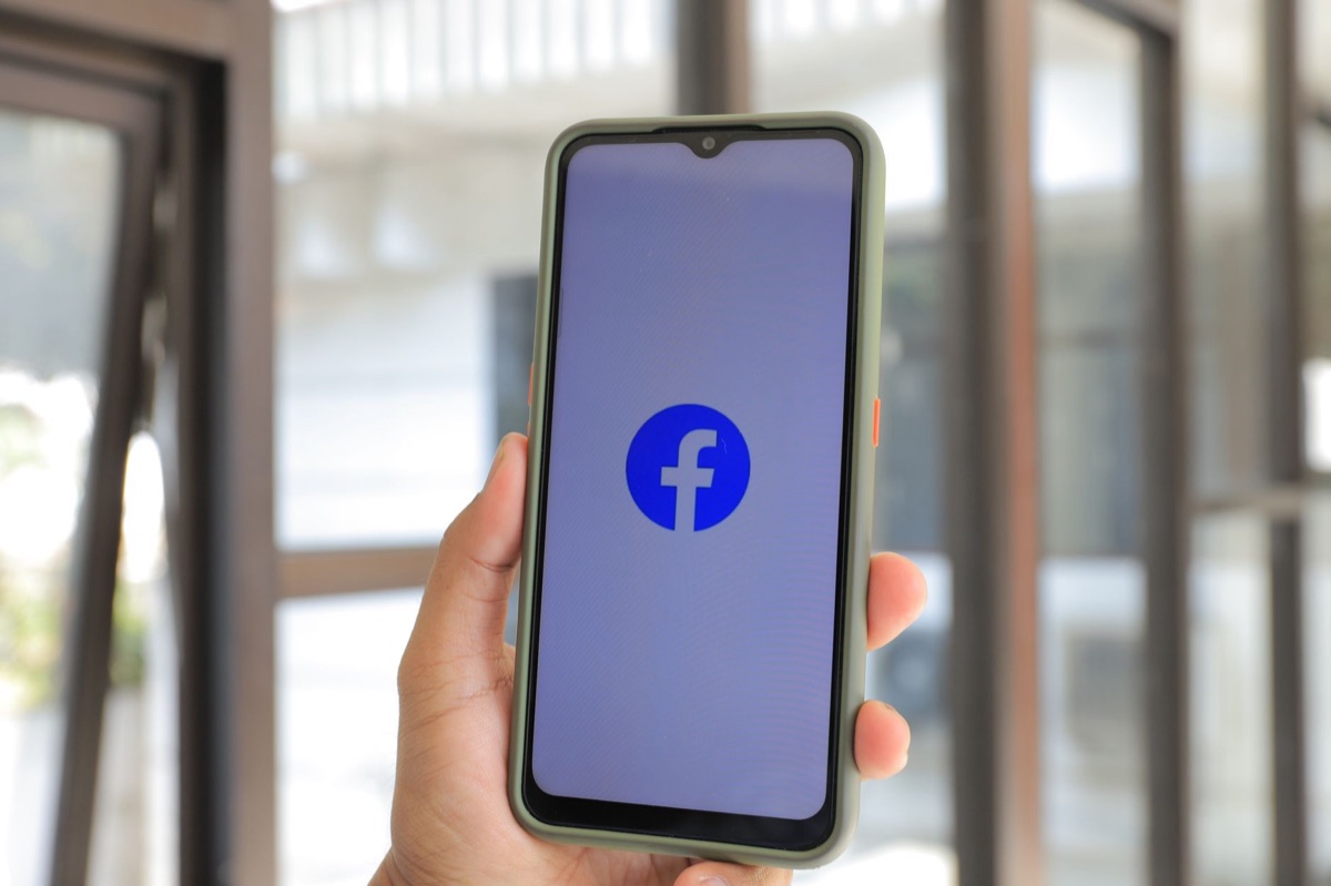 Mão segurando celular com feed ativo